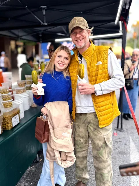 Two customers holding pickles on a stick at our stand