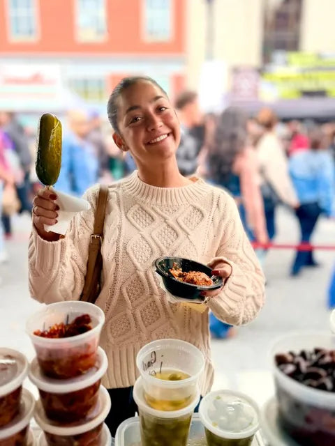 Customer holding up a pickle on a stick at a street fair